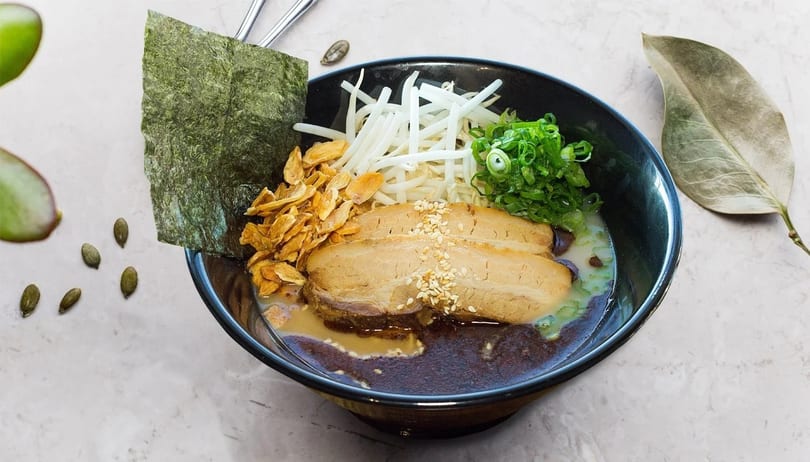 Ramen bowl with pork belly, bean sprouts, green onions, crispy garlic, and nori.