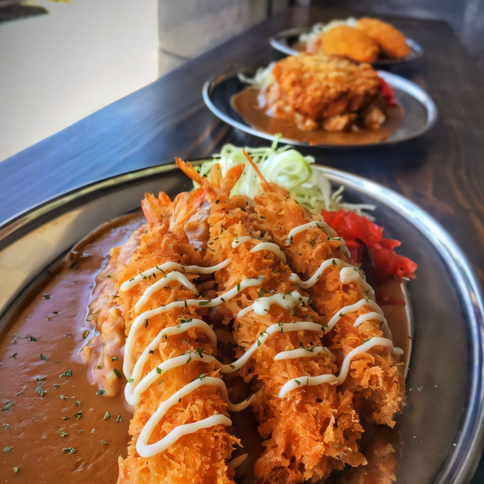 Three plates of Japanese curry with fried shrimp and cutlets, garnished with mayonnaise and herbs.